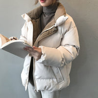 Frau in weißer Daunenjacke, hält ein Buch, Wintermode, warme Oberbekleidung, stilvoll.