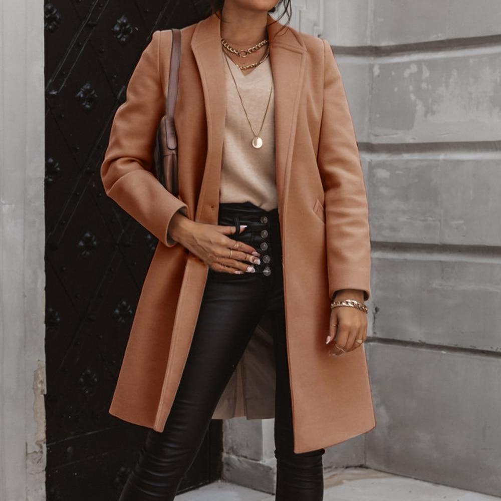 Frau in braunem Wollmantel, schwarze Lederhose, goldene Accessoires, modisch, elegant.