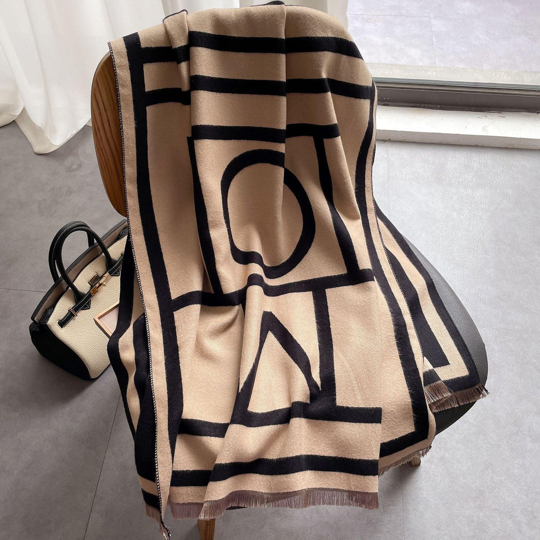 Beige Wollschal mit schwarzem geometrischem Muster auf Stuhl, luxuriöses Accessoire.