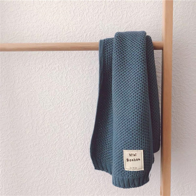 Dunkelgrüne Strickdecke aus Baumwolle, hängend, weiche Textur, ideal für Wohnzimmer-Dekor.