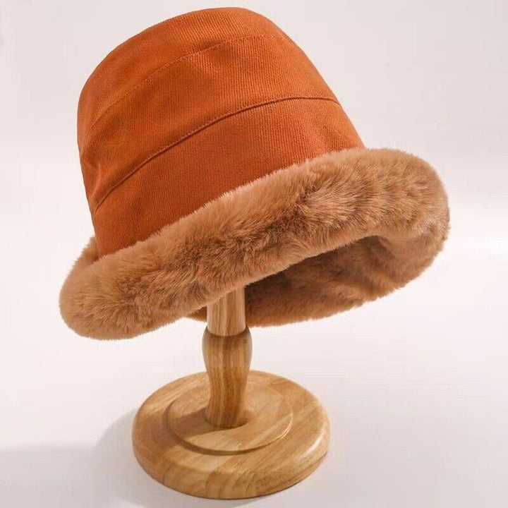 Brauner Eimerhut mit Kunstfellrand auf Holzständer, modisch, warm, Winteraccessoire.