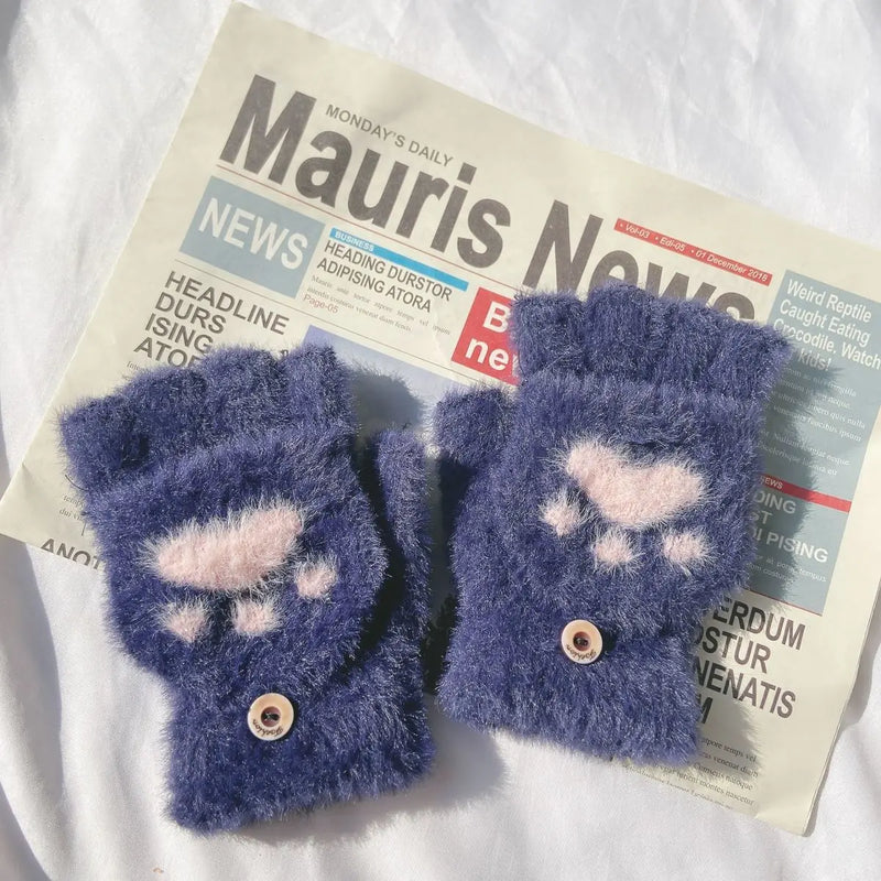 Blaue flauschige Fingerlose Handschuhe mit Pfotenmuster auf Zeitung, Wintermode Accessoire.