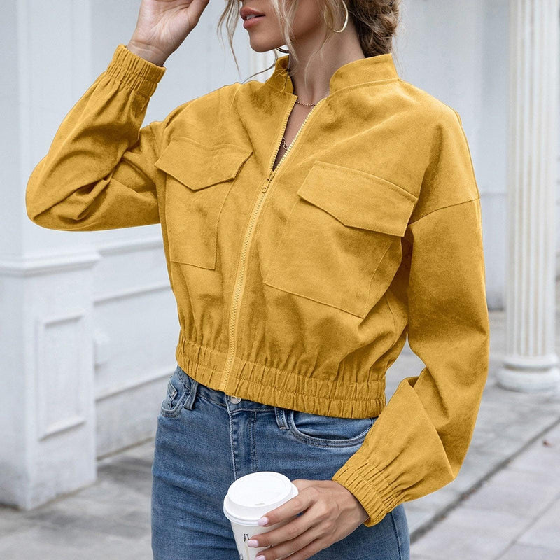Frau in gelber Wildlederjacke mit Reißverschluss, lässig, modisch, hält Kaffeebecher.
