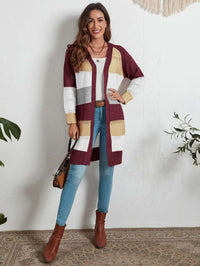 Frau trägt gestreifte Strickweste in Rot, Weiß, Gelb; kombiniert mit Jeans und braunen Stiefeln.