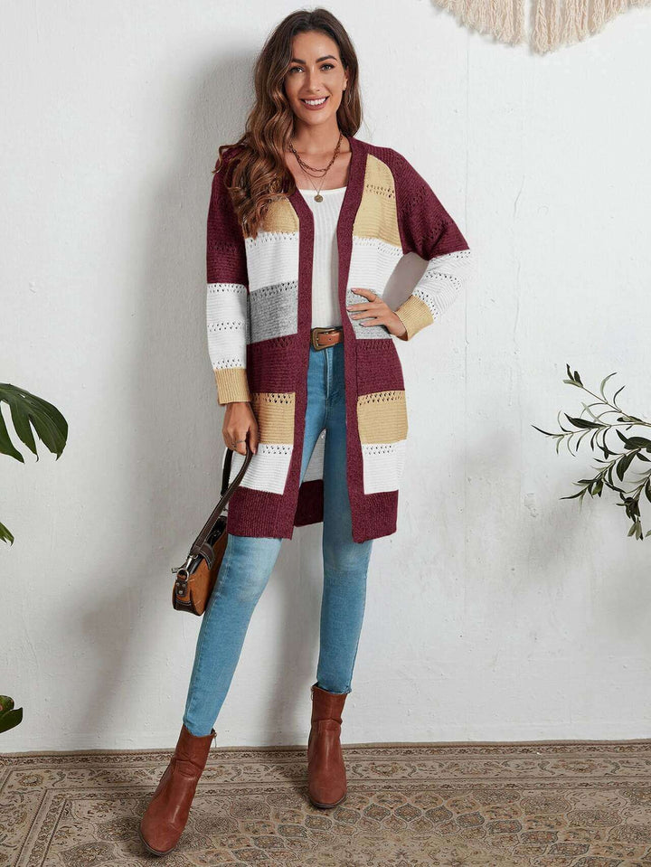 Frau trägt gestreifte Strickweste in Rot, Weiß, Gelb; kombiniert mit Jeans und braunen Stiefeln.