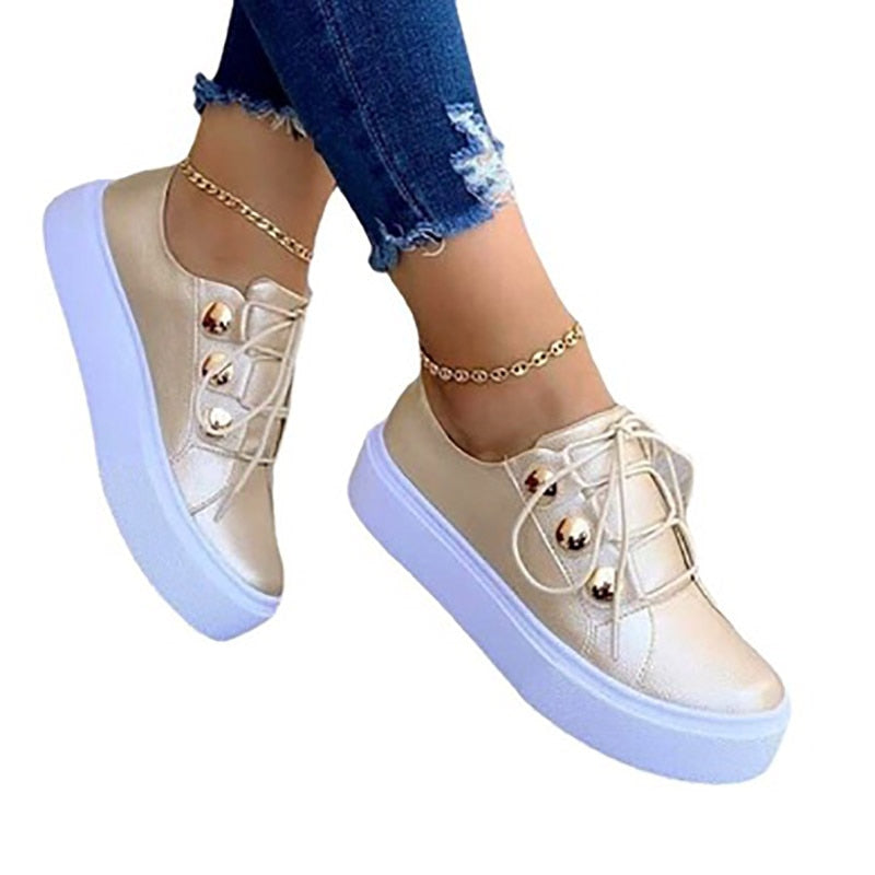 Goldene Damen-Sneaker mit Plateau, Schnürsenkeln und Jeans, modische Freizeitschuhe.