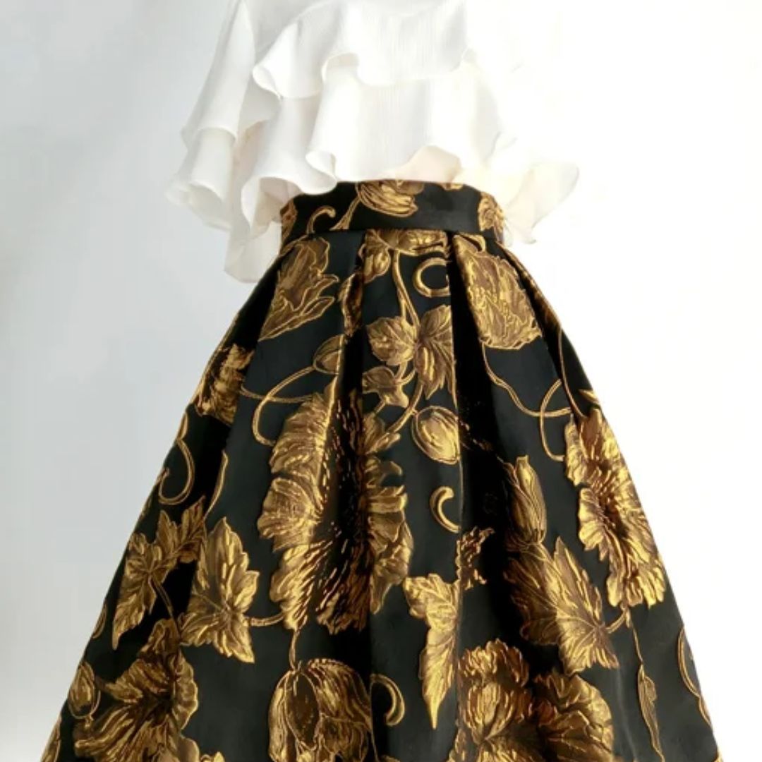 Weißes Rüschenoberteil und schwarzer Rock mit goldenen Blumenmuster, elegantes Damenoutfit.