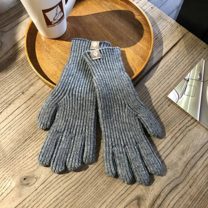 Graue Strickhandschuhe aus Wolle auf Holztisch, ideal für Wintermode und kaltes Wetter.
