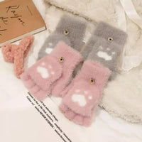 Flauschige rosa und graue Fingerlose Handschuhe mit Pfotenmuster auf weißem Bett.