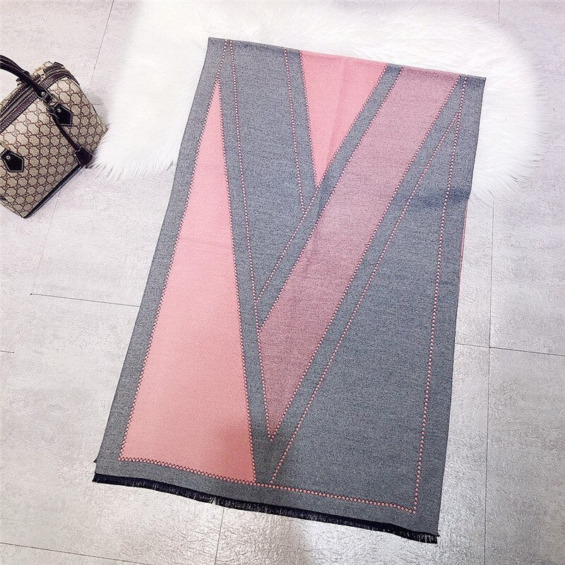 Grauer und rosa Schal mit geometrischem Muster auf Fliesenboden, modisches Accessoire.