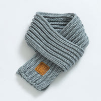 Grauer Strickschal mit Lederetikett, modisches Accessoire, warm, weich, Winterkleidung.