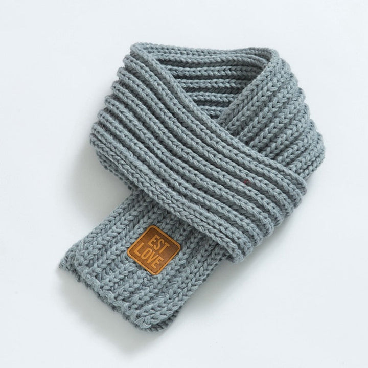 Grauer Strickschal mit Lederetikett, modisches Accessoire, warm, weich, Winterkleidung.