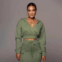 Frau in grünem Kapuzen-Crop-Top und Jogginghose, Freizeitmode, sportlich, modern.