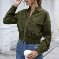 Frau in olivgrüner Jacke mit Reißverschluss, Jeans, hält Kaffeebecher, modisch, urbaner Stil.