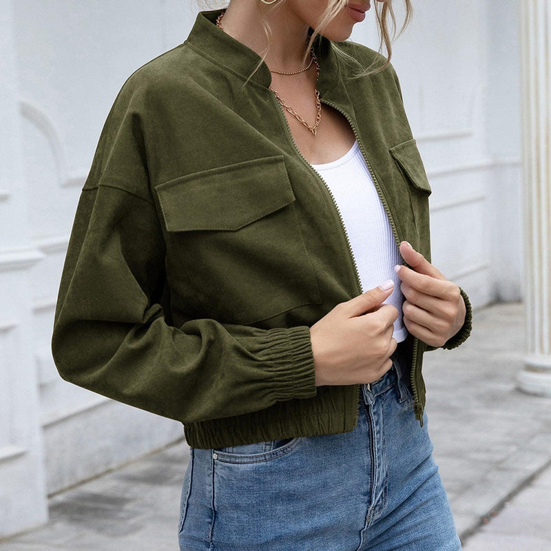 Frau trägt olivgrüne Bomberjacke, weiße Bluse, blaue Jeans, modisch, lässig, urbaner Stil.