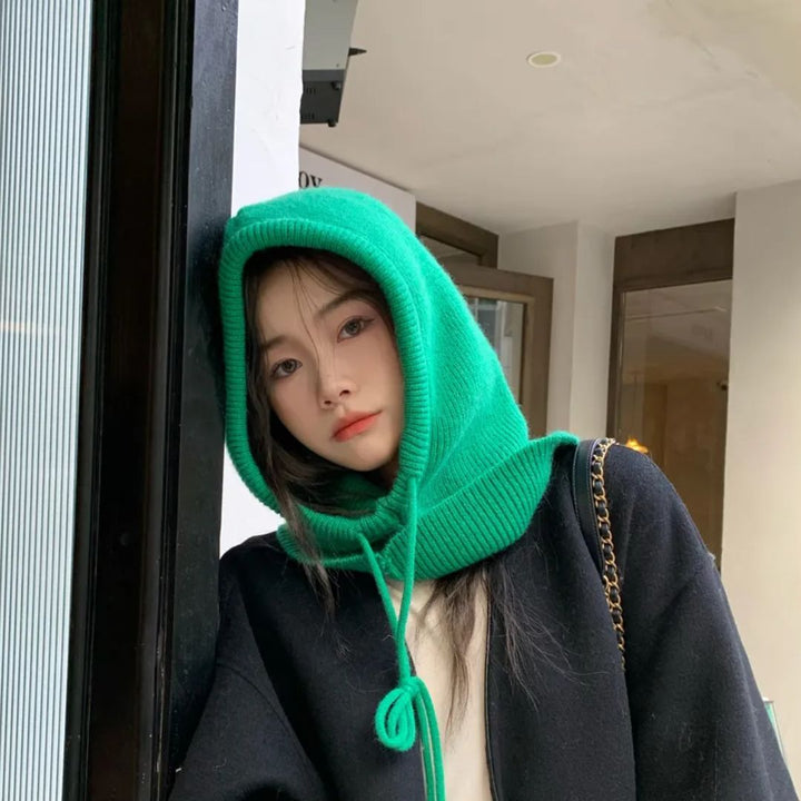 Frau mit grünem Strickschal, Kapuze, schwarzer Mantel, modisch, urbaner Stil.