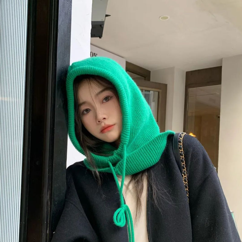 Frau mit grünem Strickschal, Kapuze, schwarzer Mantel, modisch, urbaner Stil.