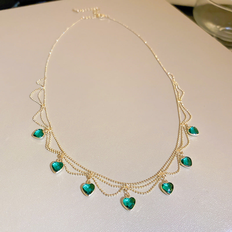 Goldene Halskette mit grünen Herzanhängern, eleganter Schmuck, Damenaccessoire.