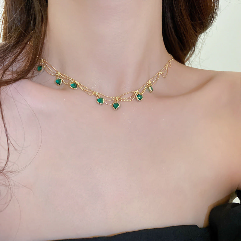 Goldene Halskette mit grünen Herzanhängern, eleganter Schmuck für Damen.
