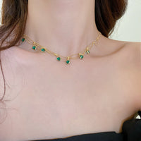 Goldene Halskette mit grünen Herzanhängern, eleganter Schmuck für Damen.