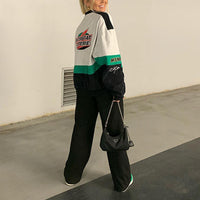 Frau in bunter Bomberjacke, schwarze Hose, Prada-Tasche, lässiger Streetstyle-Look.