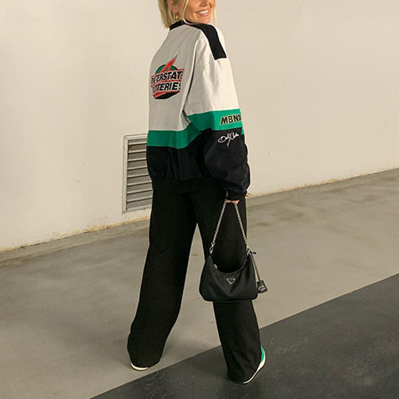 Frau in bunter Bomberjacke, schwarze Hose, Prada-Tasche, lässiger Streetstyle-Look.