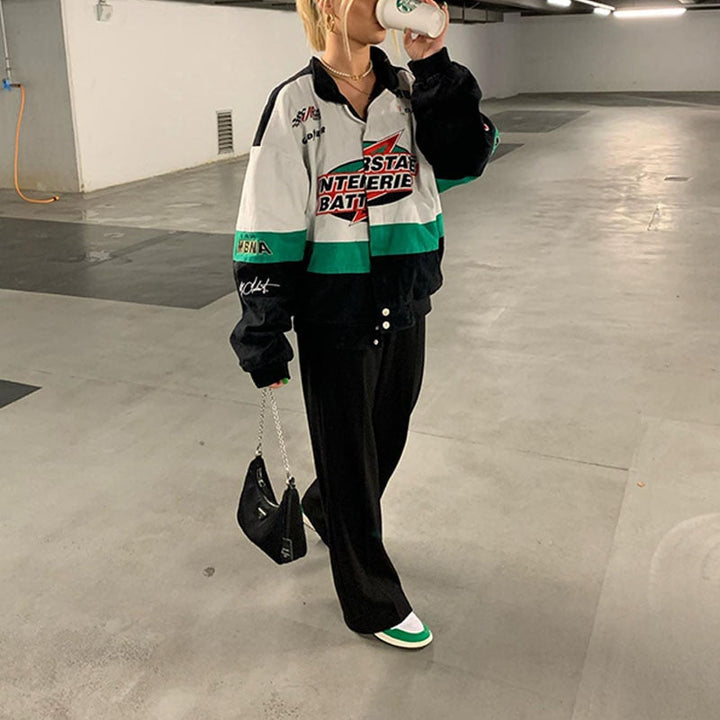 Frau in bunter Windjacke, schwarze Hose, weiße Sneaker, Tiefgarage, Mode, Streetwear.