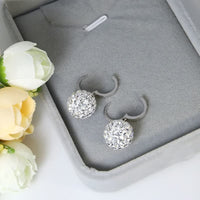 Silberne Ohrringe mit Kristallen in grauer Schmuckschatulle, eleganter Schmuck für Damen.