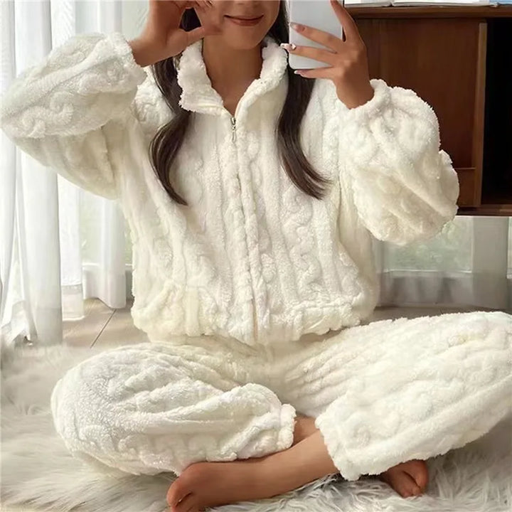 Frau in weißem, flauschigem Fleece-Pyjama-Set, sitzt auf Teppich, gemütliche Winterkleidung.