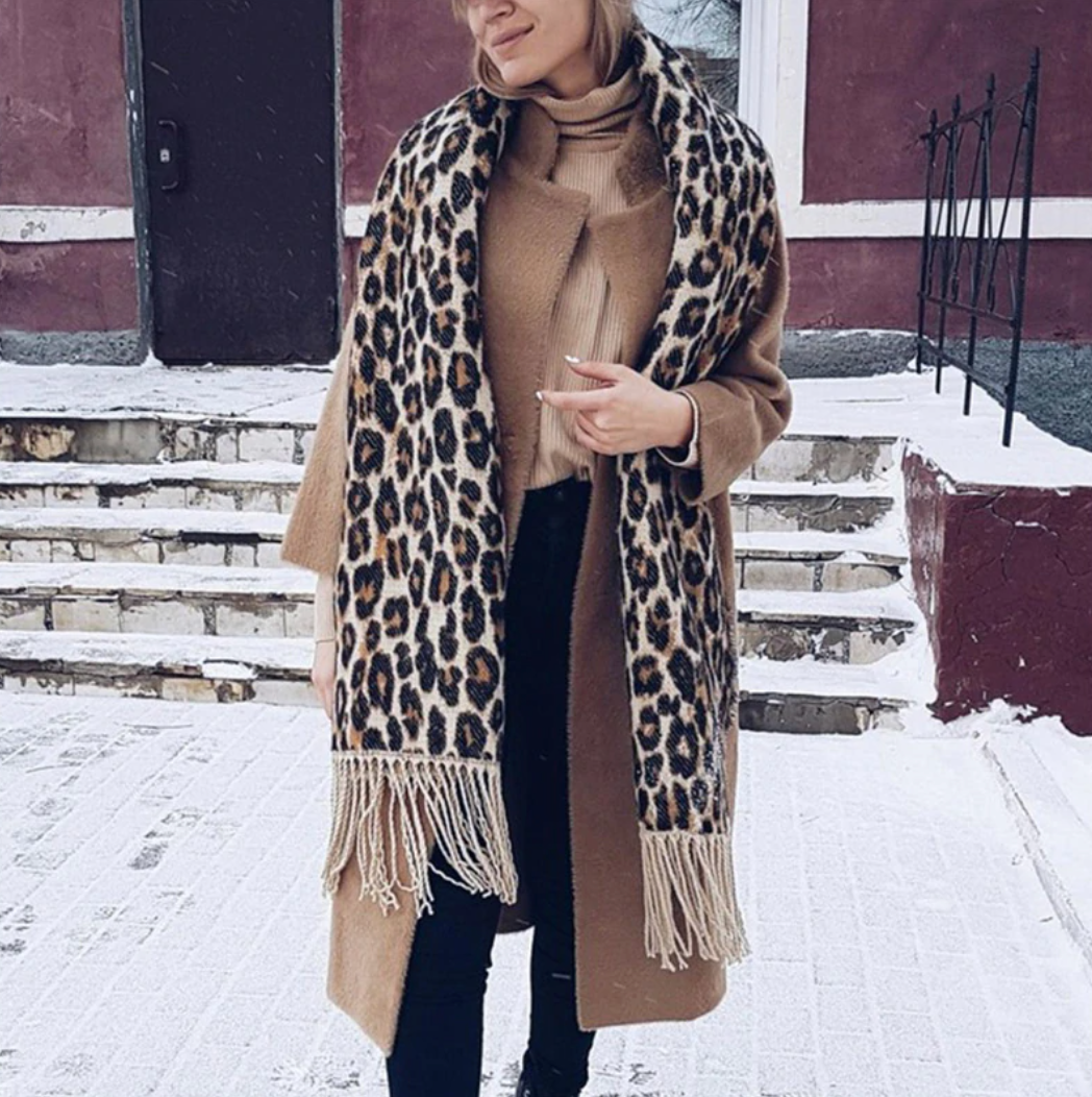 Frau mit braunem Mantel und Leopardenmuster-Schal im Schnee, Wintermode, stilvoll, warm.