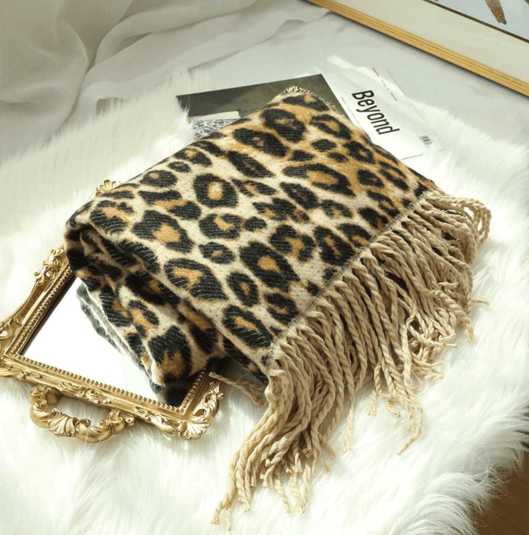 Leopardenmuster Decke mit Fransen auf Spiegel, luxuriöses Wohnaccessoire, weiches Material.