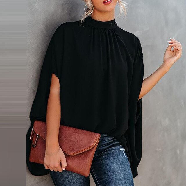 Frau in schwarzer Batwing-Bluse mit brauner Clutch, lässiger Look, Mode für Frühling und Sommer.