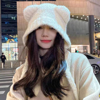 Frau mit weißem Plüsch-Bärenohren-Hut, Wintermode, urbaner Hintergrund.